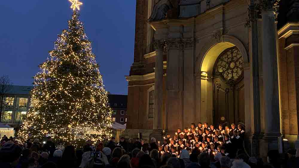 Michel-Eingang bei Dämmerung, daneben leuchtet ein großer Weihnachtsbaum