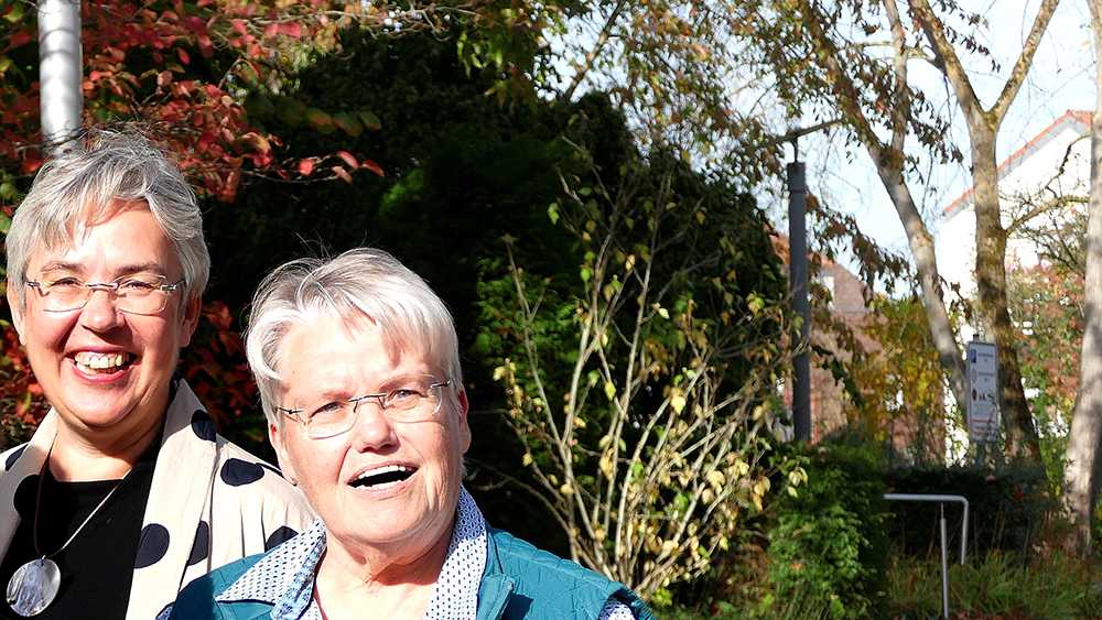 Die Vorsitzende Angelika Waldheuer (links) und die Leitende Pfarrerin Birgit Reiche vor einem grünen Strauch