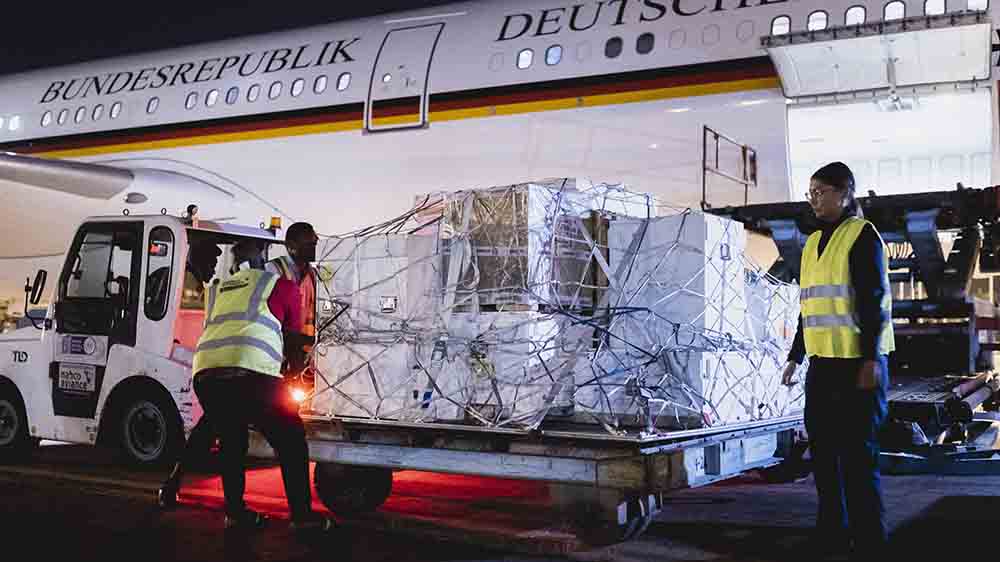 Flugzeug mit Deutschland-Fahne, aus dem Gepäckraum werden große Kisten geholt