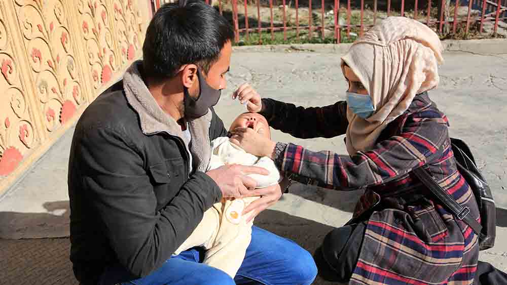 Ein Kind bekommt in Kabul eine Polio-Impfung von einer Frau verabreicht