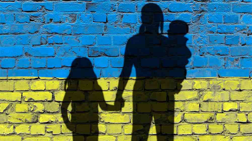 Silhouette einer Frau mit Kind vor ukrainischer Flagge