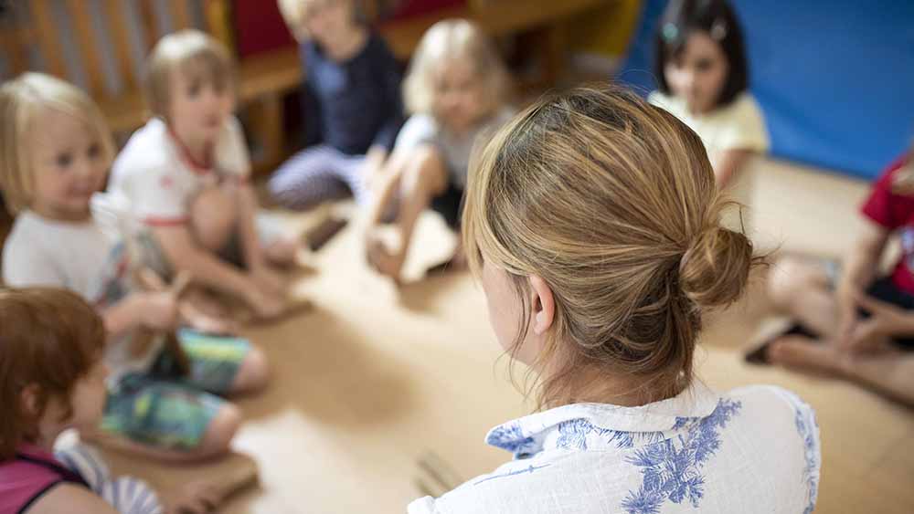 Kreis mit kleinen Kindern, Erzieherin spricht