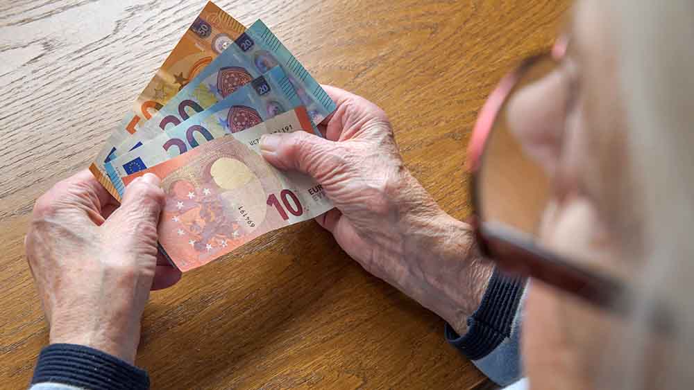 Seniorin über die Schulter fotografiert, mit drei Geldscheinen in der Hand