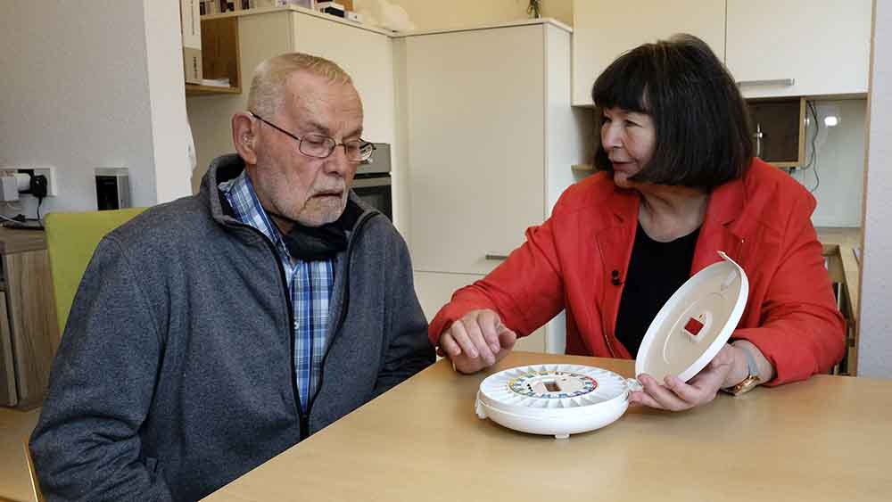 Jutta Heinrich zeigt Martin Rudat, wie ein automatischer Tablettenspender funktioniert