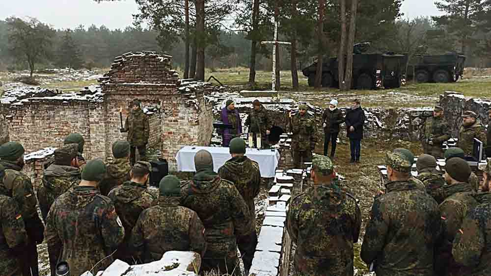 Soldaten feiern Gottesdienst auf Wiese vor Panzer