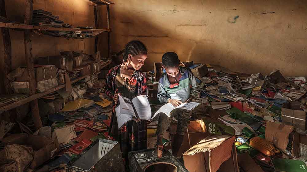 Mitten in der zerstörten Bibliothek einer Grundschule in der äthiopischen Region Tigray lesen diese beiden Kinder