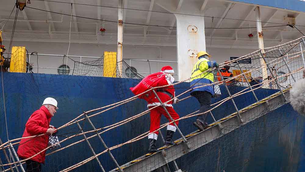 Weihnachtsmann geht über Gangway auf ein Frachtschiff
