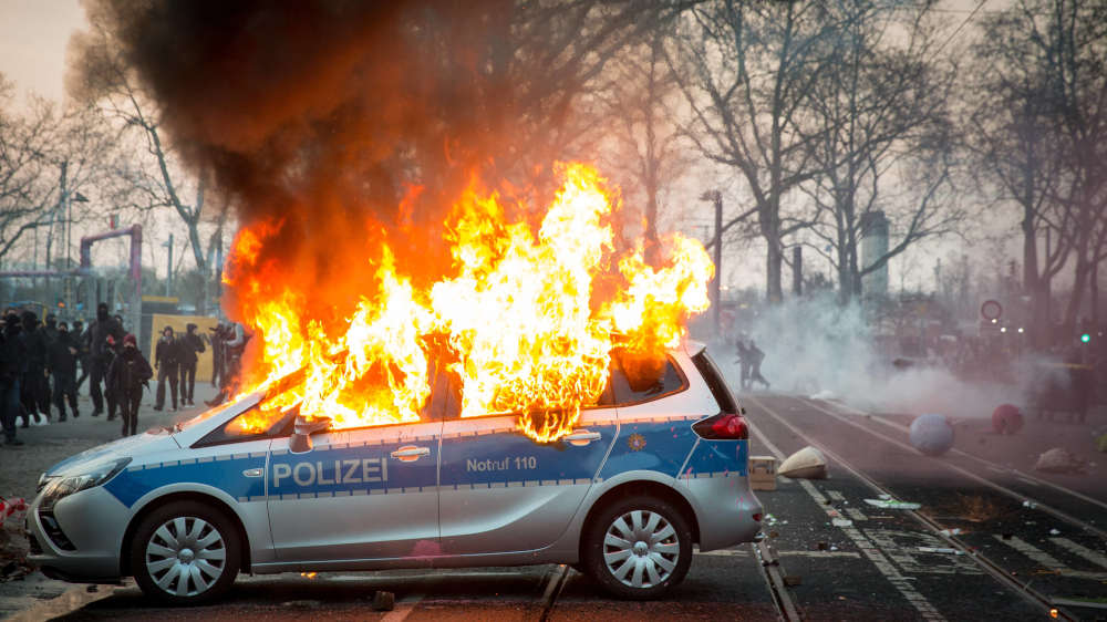 Ein von Demonstranten bei Protesten in Frankfurt am Main angezündeter Polizeiwagen