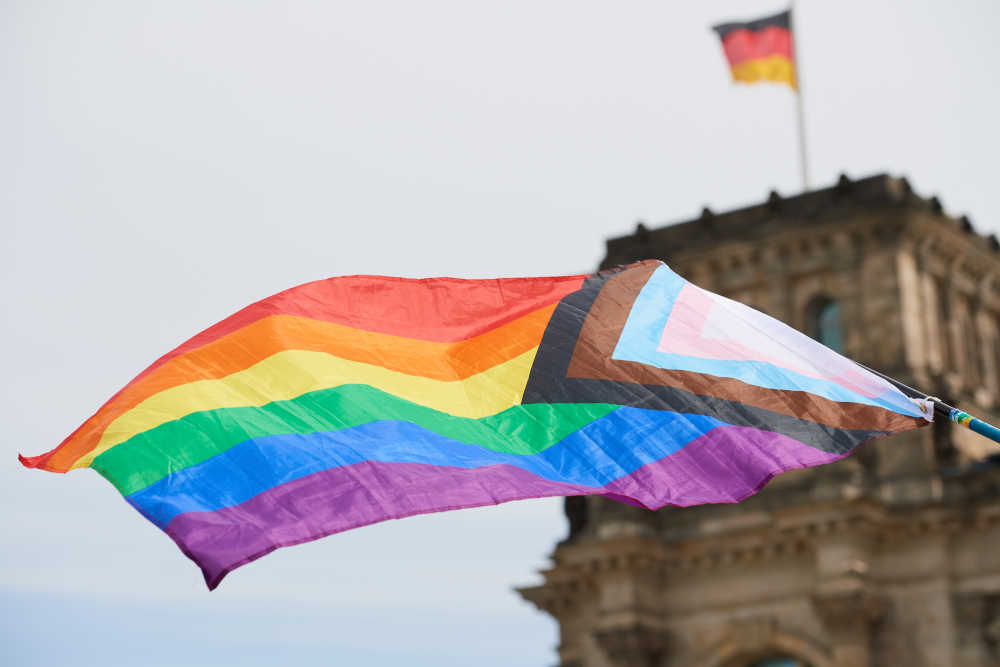 Eine LGBTQ Regenbogenfahne vor dem Reichstagsgebaeude in Berlin