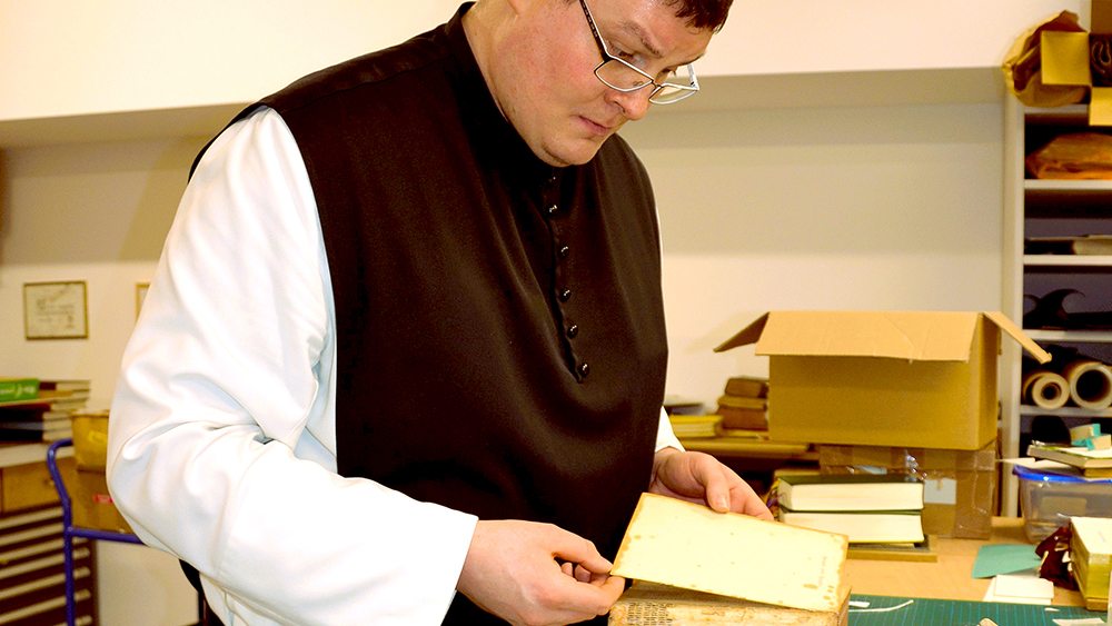 Erst einmal sieht sich Pater Matthias das zu bearbeitende Buch ganz genau an.