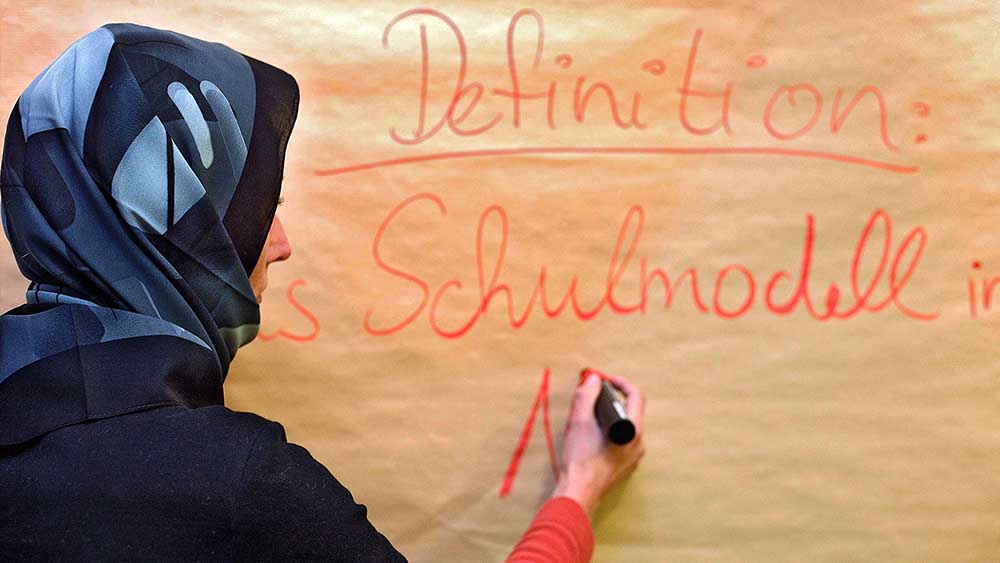 Frau mit Kopftuch schreibt an Tafel