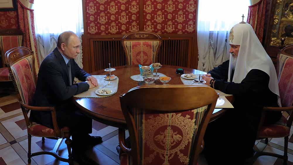 Putin und Kyrill sitzen an einem Tisch und sprechen miteinander