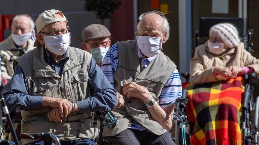 5 Senior:innen sitzen in Rollstühlen, alle haben eine Maske auf.