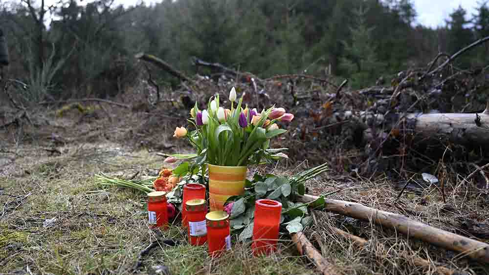 Blumen und Kerzen stehen an einer Lichtung in einem Wald