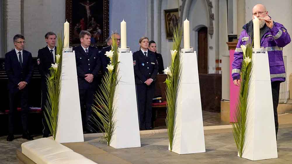 Diakon Lutz Neugebauer entzündet eine Kerze für die Opfer