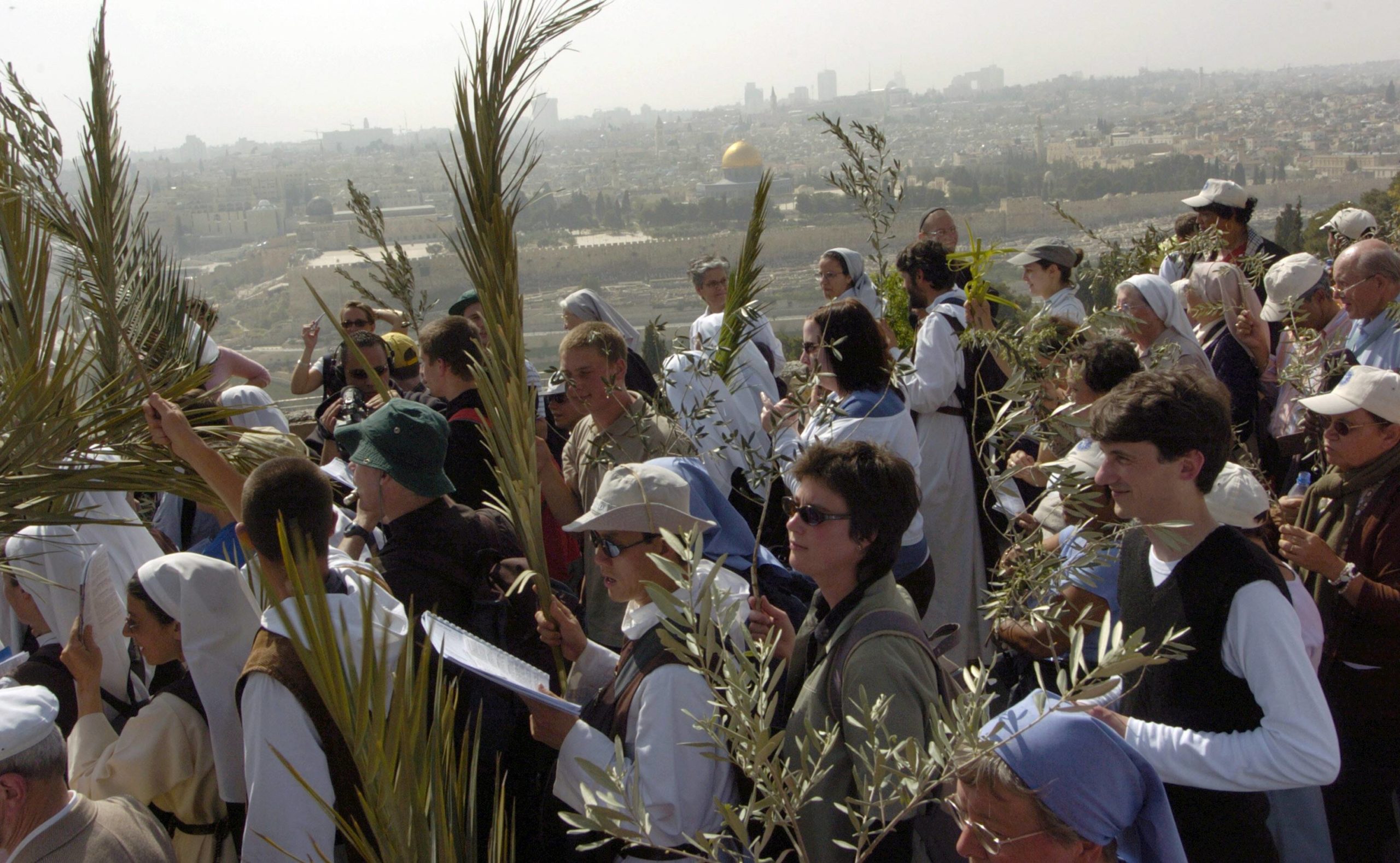 Christen tragen Palmenwedel und Olivenzweige während der Palmprozession am Palmsonntag in Jerusalem