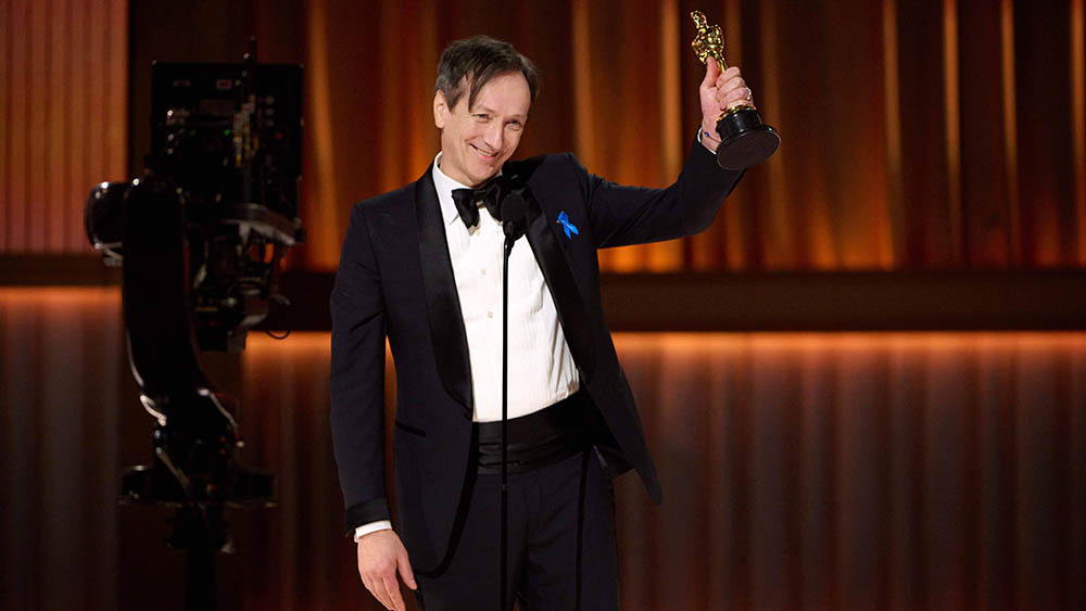 Mann mit Smoking halt Oscar-Trophäe nach oben