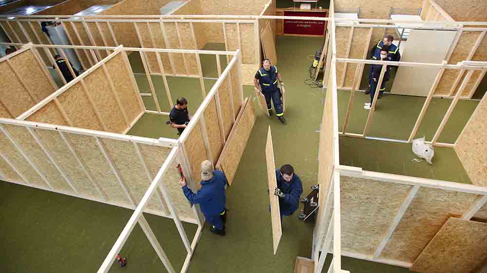 In einer Sporthallen werden aus Holz einzelne Kabinen gebaut