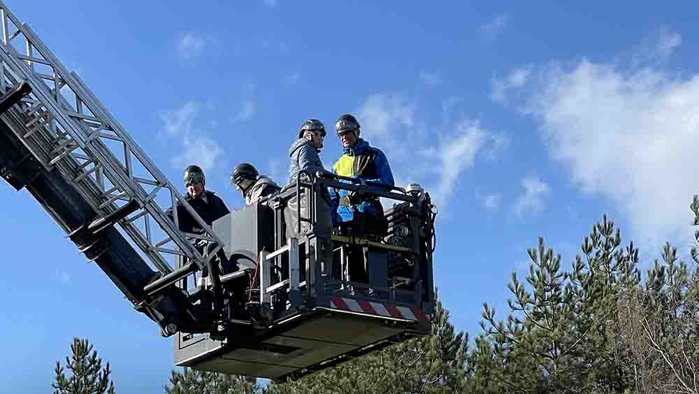 Auf einer Feuerwehr-Hebebühne stehen mehrere Personen