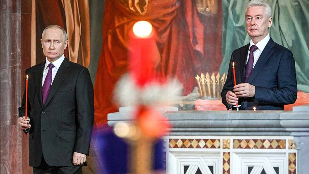 In einem Gottesdienst in Moskau halten der russische Machthaber Wladimir Putin und Moskaus Bürgermeister Sergej Sobjanin eine rote Kerze