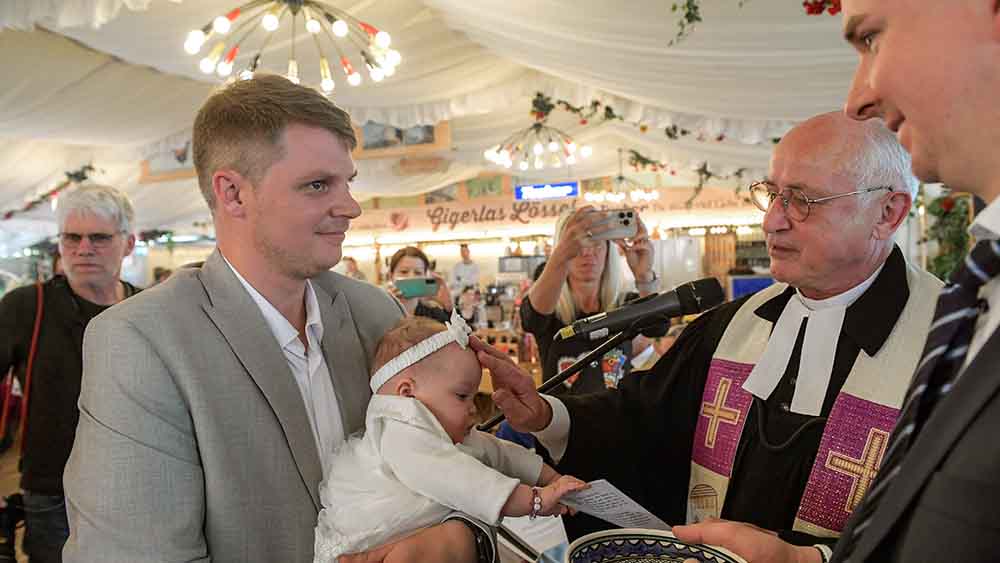 In einem Festzelt in Nürnberg tauft Pfarrer Johannes Bräuchle diese kleine Christin