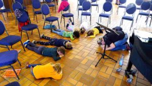 Die Chorkinder liegen während einer Entspannungseinheit auf dem Boden.