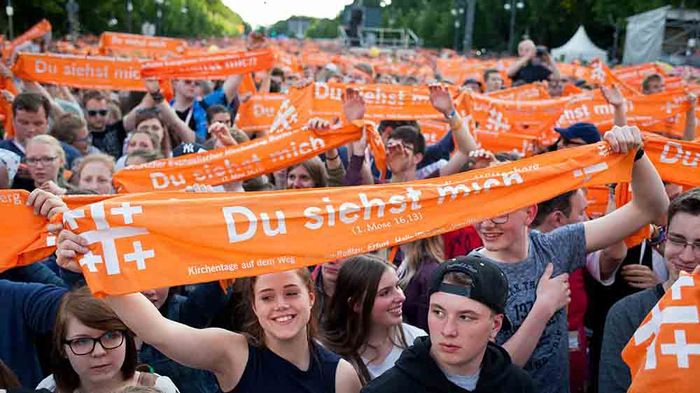 Menschenmenge hält orangefarbene Schals in die Höhe