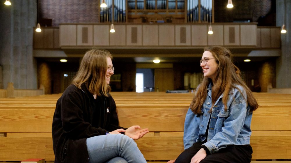 Zwei junge Frauen unterhalten sich in einer Kirche