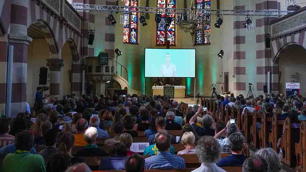 Auf der Leinwand sprechen künstliche Avatare zur Gemeinde