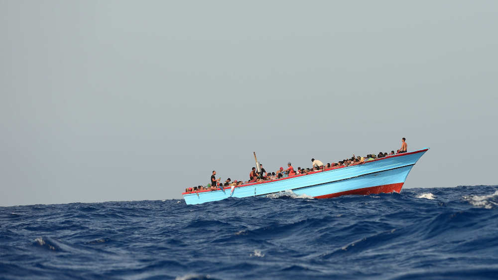 Flüchtende in einem Holzboot auf dem Mittelmeer zwischen Libyen und Lampedusa, sie gehört zu den meist frequentierten und tödlichsten