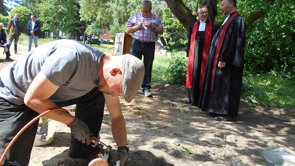 Grundsteinlegung in Walsleben – Grund zum Feiern und Beten. Zimmermann Marcel Ritthaler lötet die Zeitkapsel zu, im Hintergrund Bauausschuss-Vorsitzender Johannes Pritzkow
