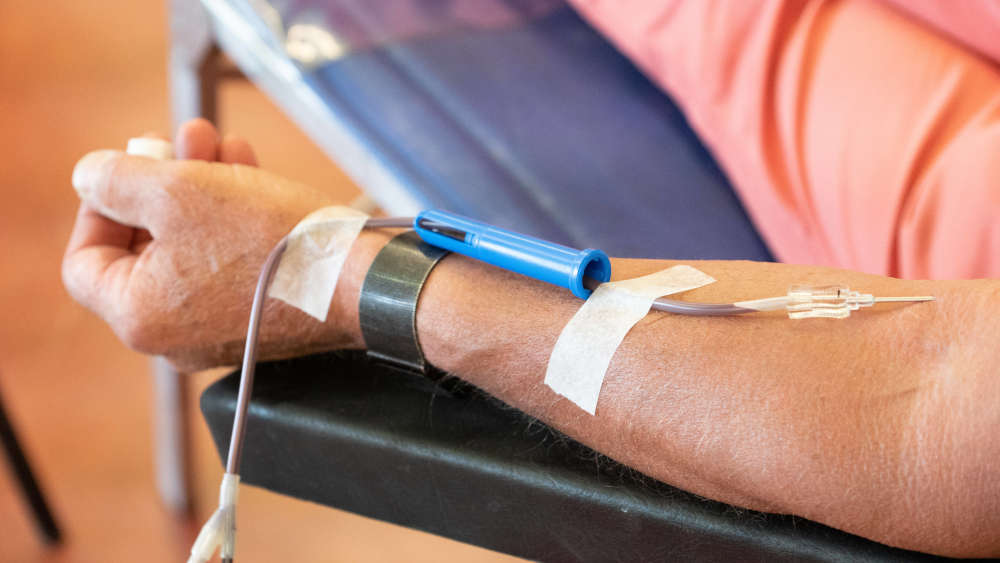 Ein Blutspender sitzt auf dem Liegestuhl und spendet Blut