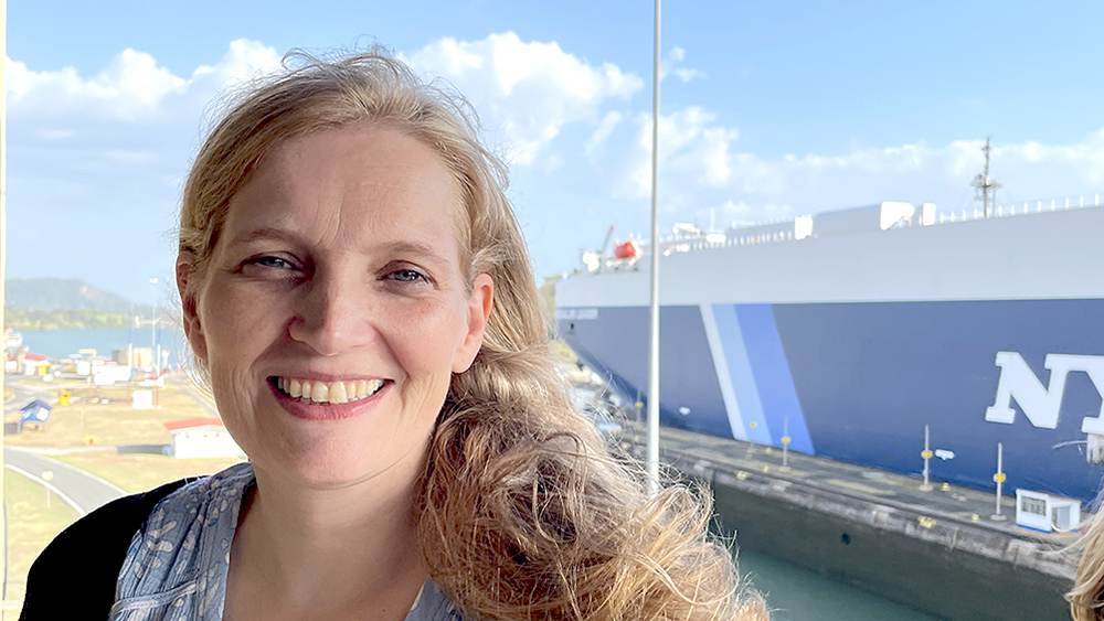 Andrea Meenken vor einem Containerschiff im Hafen.