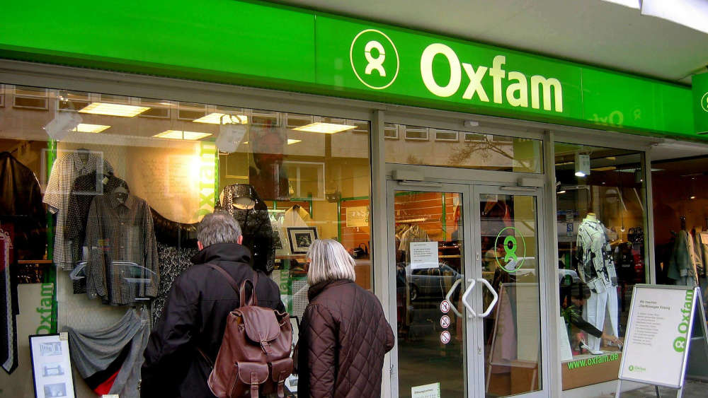 Kunden schauen sich Gebrauchtes im Schaufenster einer Oxfam-Filiale an