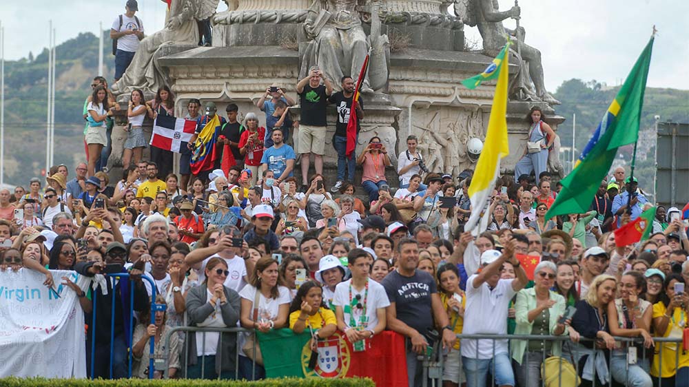 Jubelnde Jugendliche empfangen Papst Franziskus in Lissabon, es gibt aber auch Kritik und Missbrauchsbetroffene haben ein Protest-Plakat aufgehangen