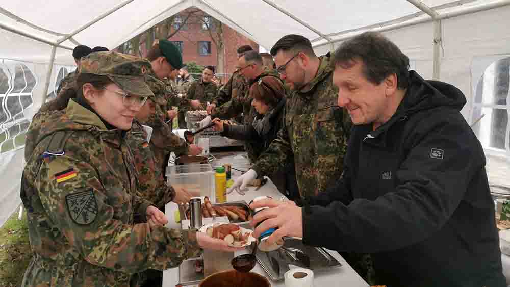 In einem Zelt geben Leute in Uniform Currywurst aus