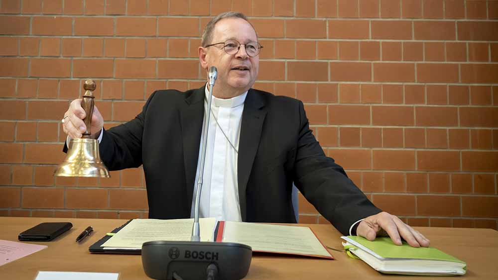Mann sitzt am Tisch und klingelt mit Glocke