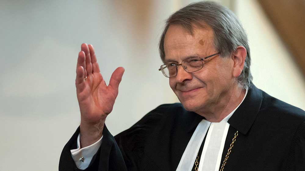Mann im Talar hebt rechte Hand