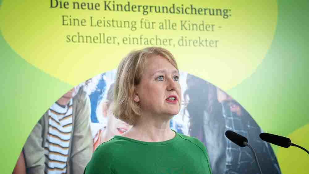 Blonde Frau im grünen Pullover steht an einem Mikro