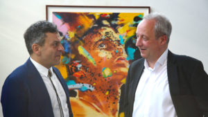 Auktionator Fares El-Hassan mit Bischof Christian Stäblein vor einem Kunstwerk von Norbert Biesky
