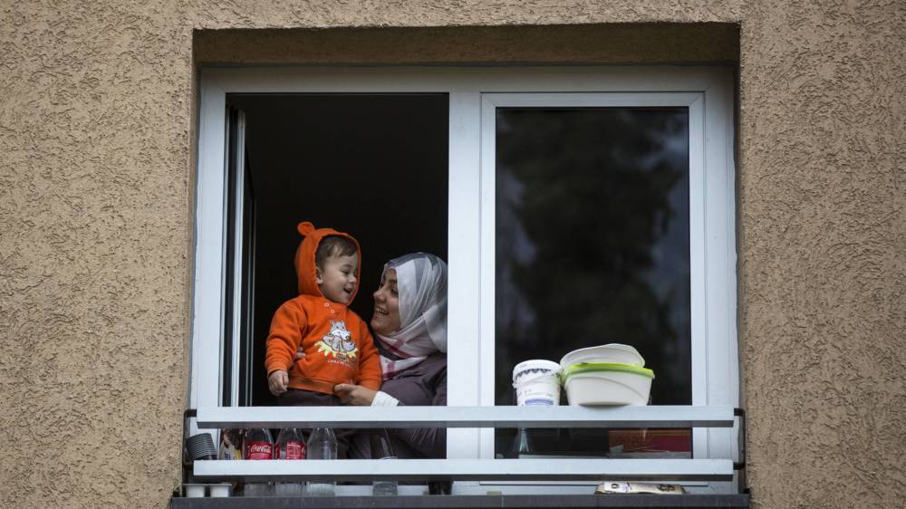 Mutter mit Kind (Flüchtlinge aus dem Irak) schauen aus einem Fenster einer Erstaufnahmeeinrichtung in Wiesbaden 