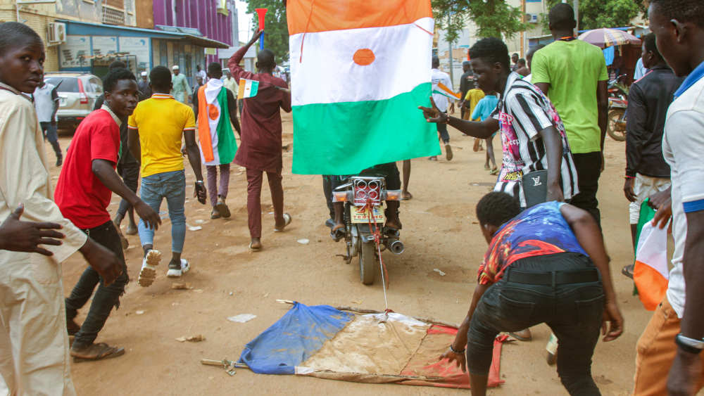 Junge Nigerianer ziehen während einer Kundgebung  vor der Nationalversammlung am 20. August 2023 in Niamey eine französische Flagge auf einem Motorrad hinter sich her (Archivbild)