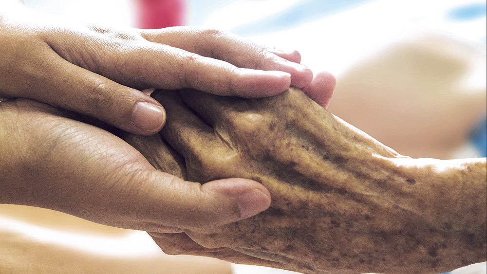 Junge Hand hält alte faltige Hand