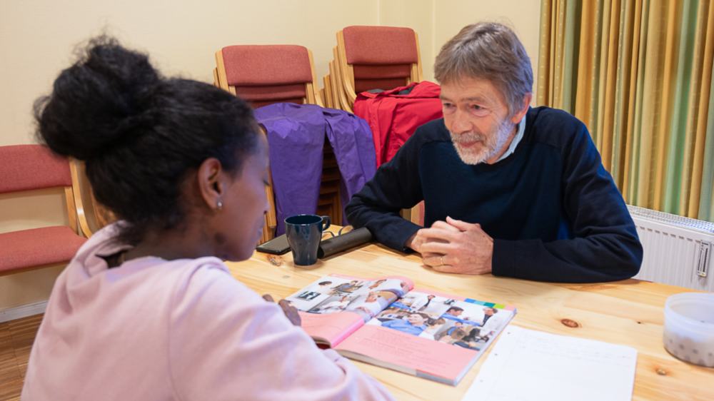 Der ehrenamtliche Lernpate Walter Langhans geht mit einer jungen Frau aus Eritrea das Deutschlehrbuch durch