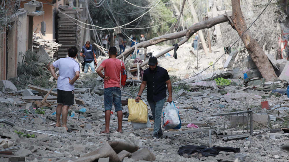 Palästinenser gehen durch Trümmer und Zerstörung auf einer Straße im Bezirk al-Karama in Gaza-Stadt