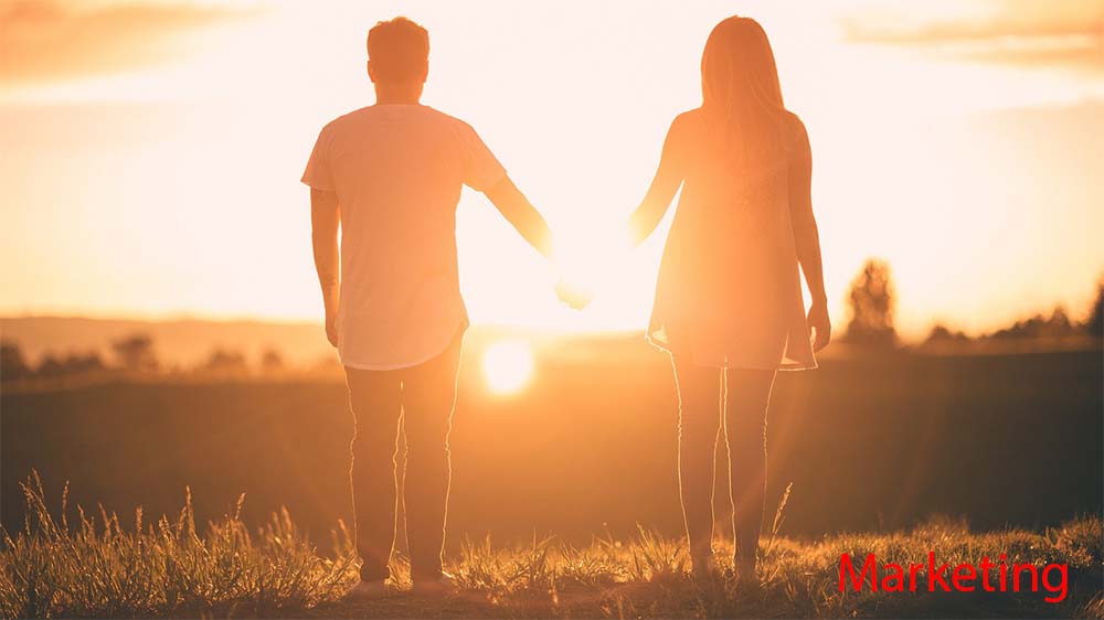 Paar geht Hand in Hand über eine Wiese im Sonnenuntergang