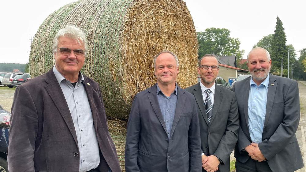 Vier Männer vor einem Strohballen