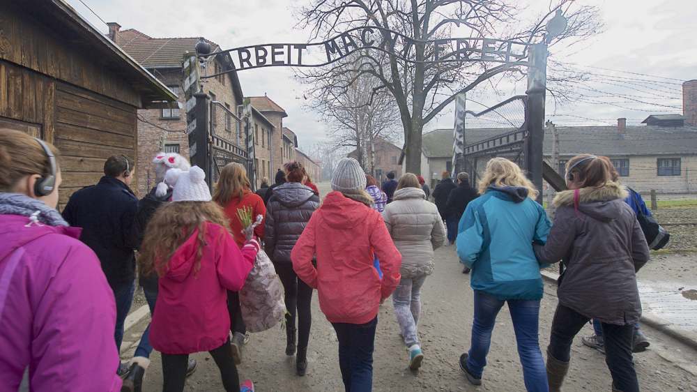 Eine Schulklasse geht durch das Eingangstor zum Konzentrationslager Auschwitz 1 in Polen