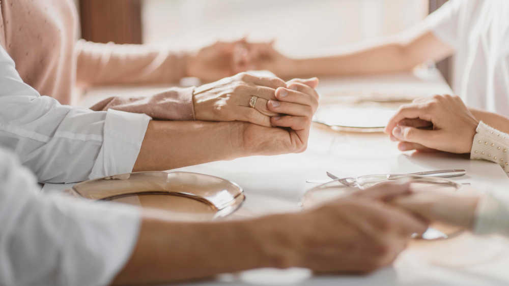 Eltern beten mit Kindern vor dem Essen