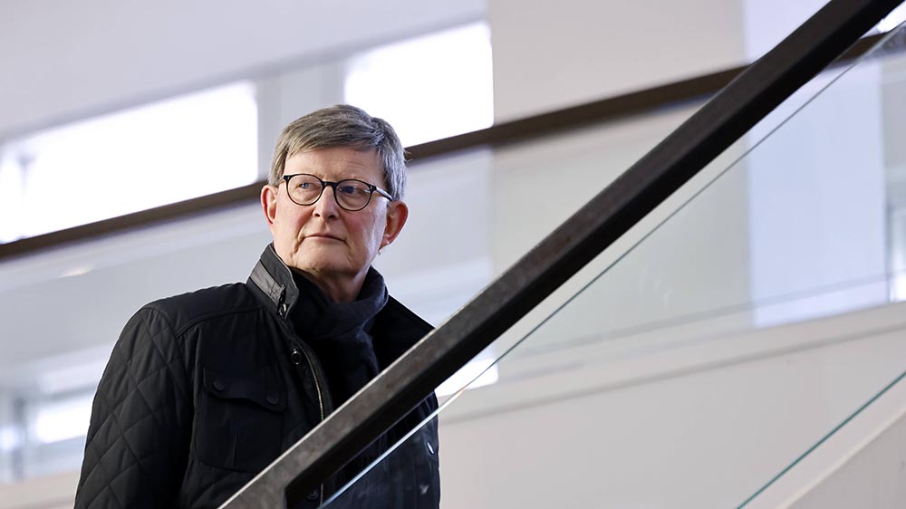 Mann mit Brille und blauer Jacke geht eine Treppe hoch